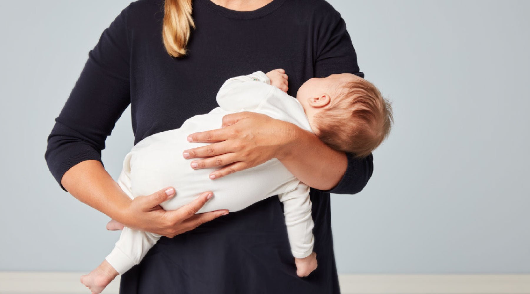 En mamma som håller sovande bebis i famnen