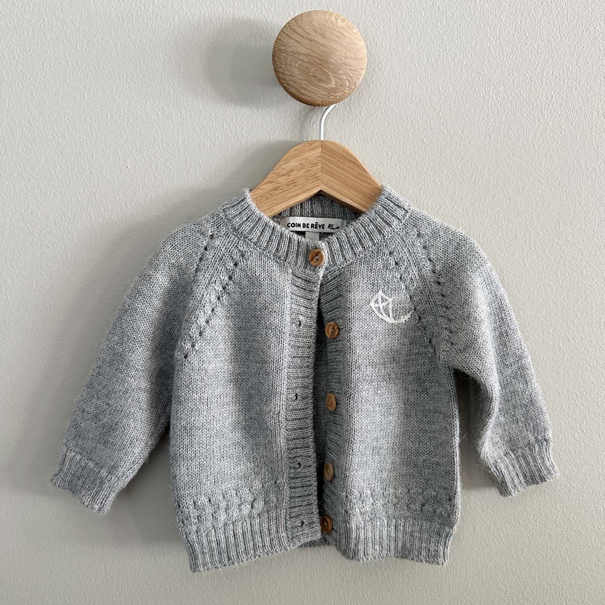 Grå kofta för baby i alpaca med hålstickade detaljer och vackert logobrodyr