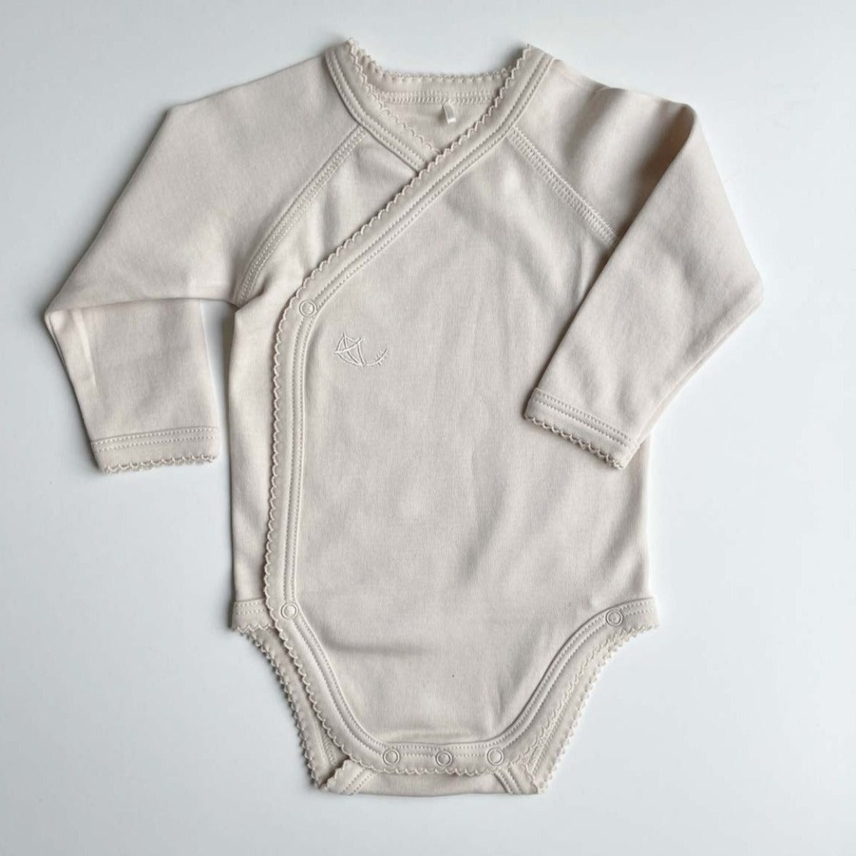 Beige omlottbody med spets för baby i mjuk ekologisk pimabomull