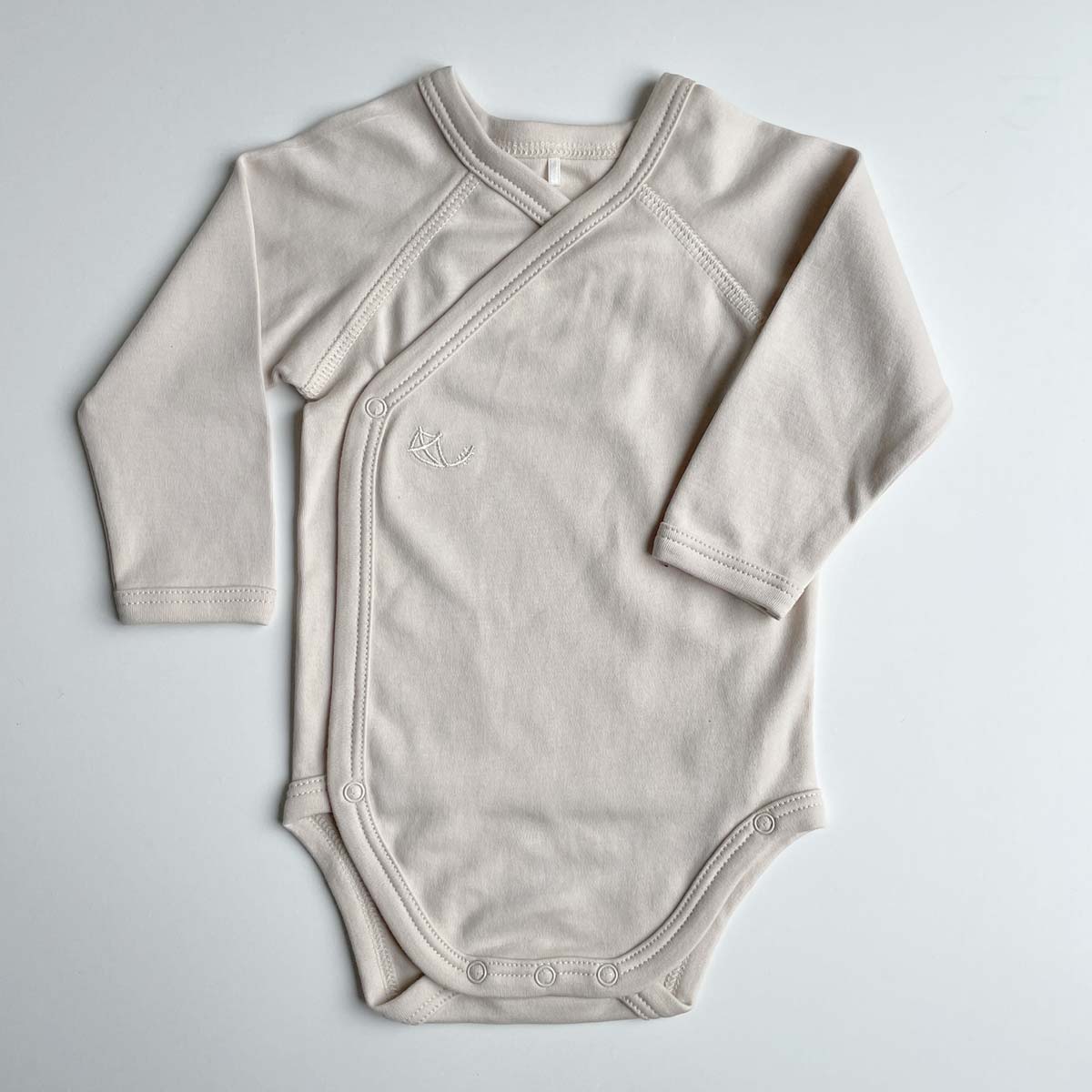 Beige omlottbody för baby i mjuk ekologisk pimabomull