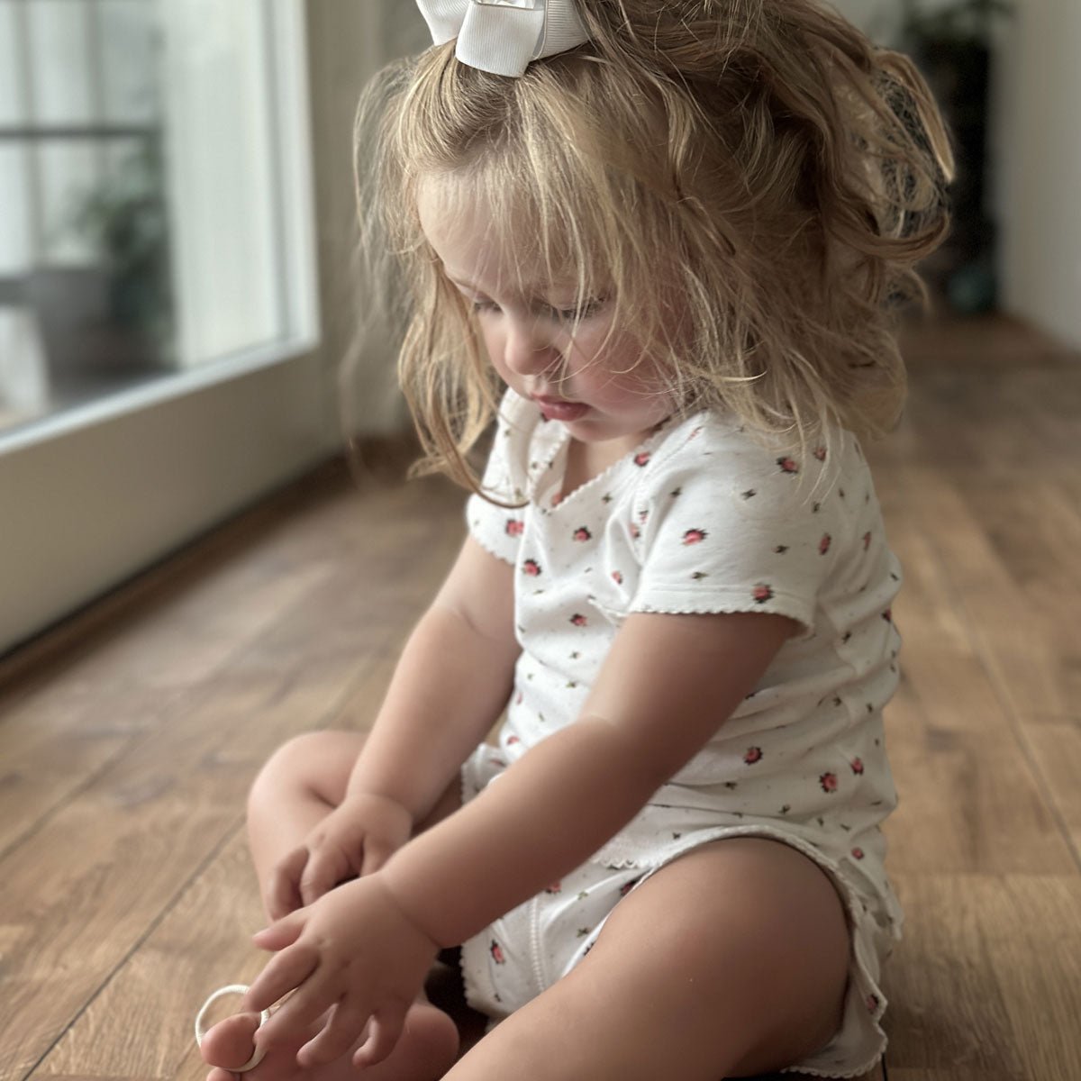 Blommönstrad kort pyjamas i vit ekologisk bomull på liten flicka som sitter ner