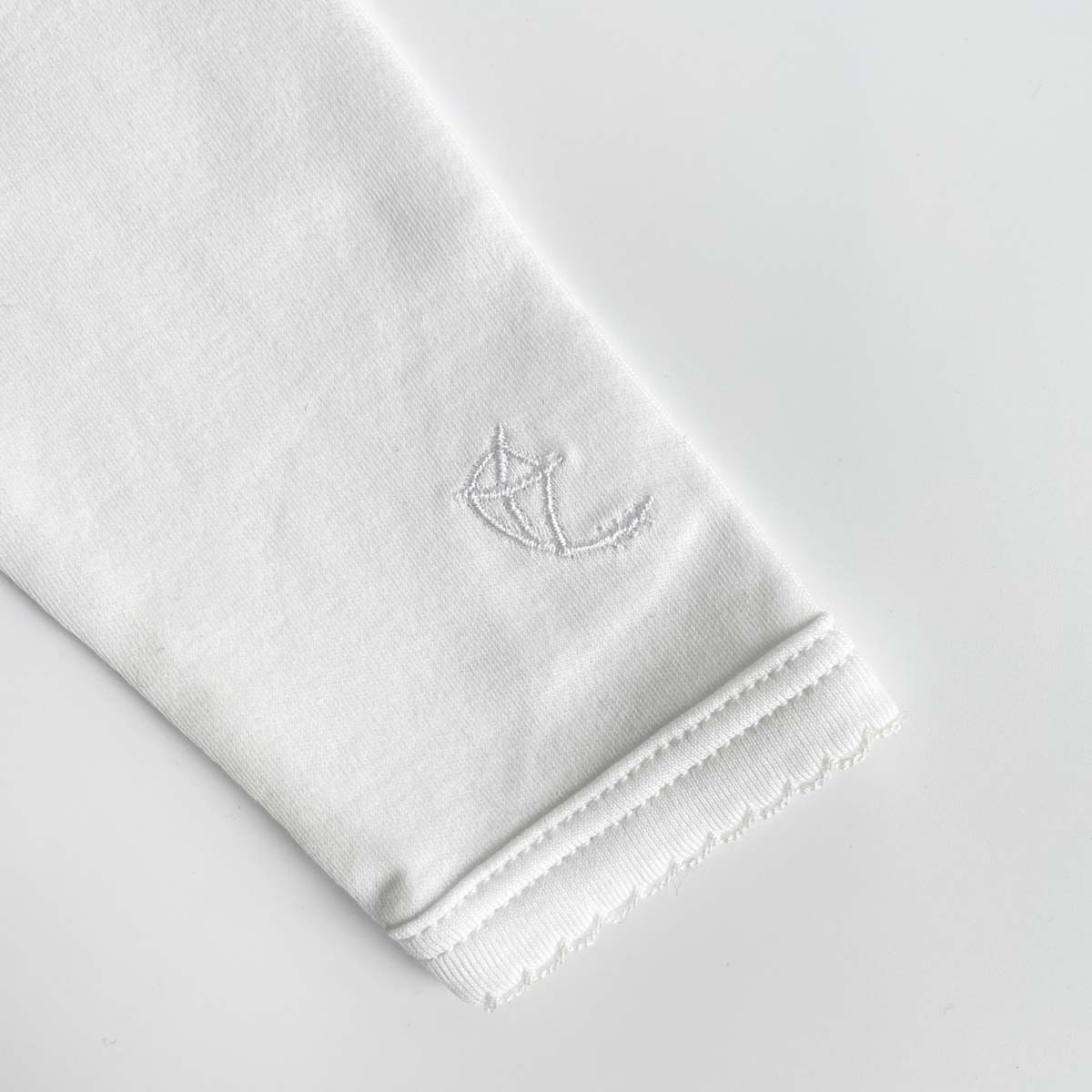 Närbild på ärm med spets på vit body med kuvertöppning i halsen