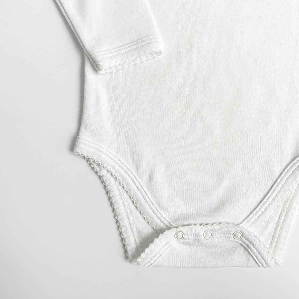 Närbild på spetsdetalj på vit body med kuverthals