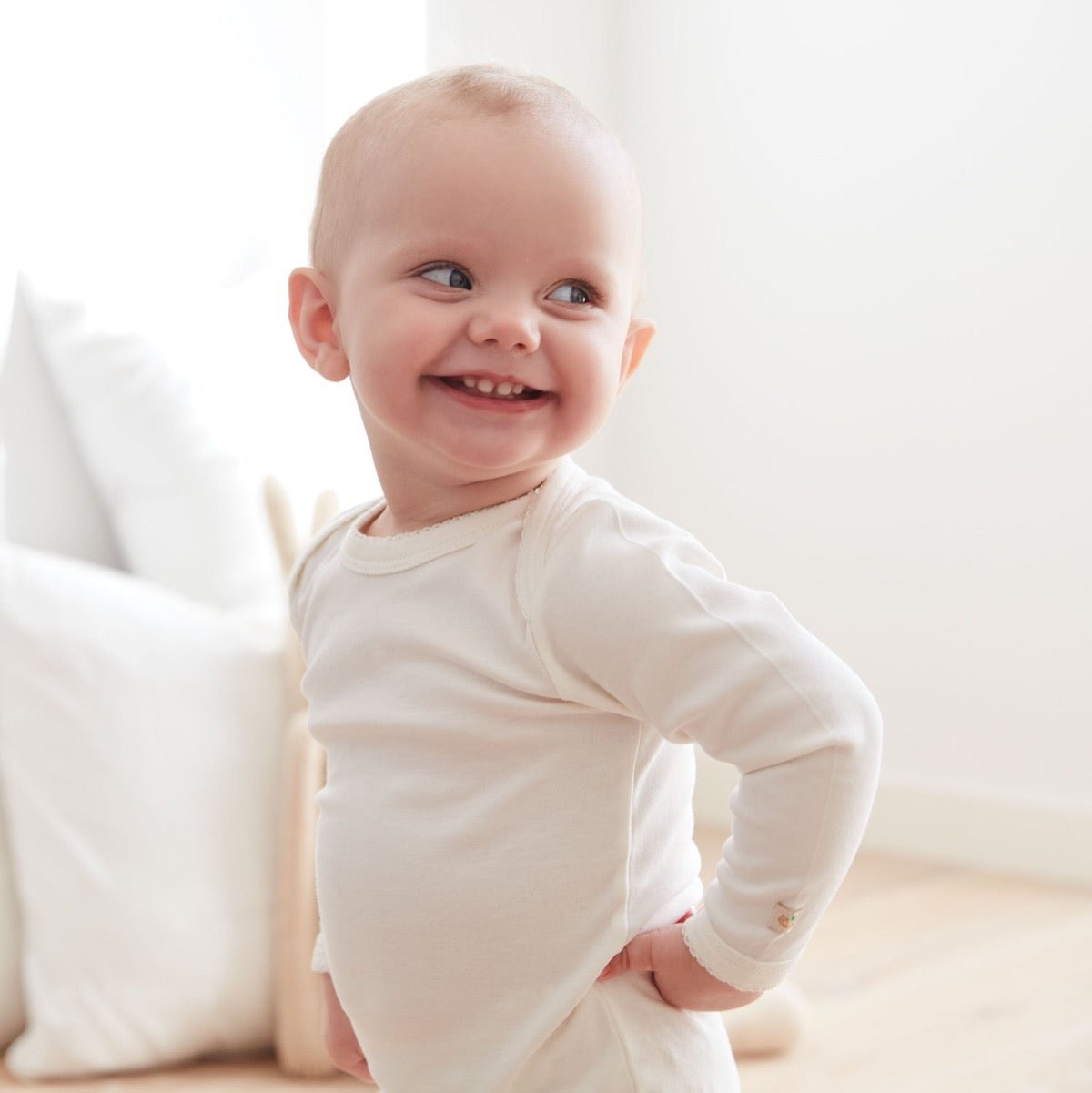 Glad baby i vit body av högsta kvalité och underbar passform