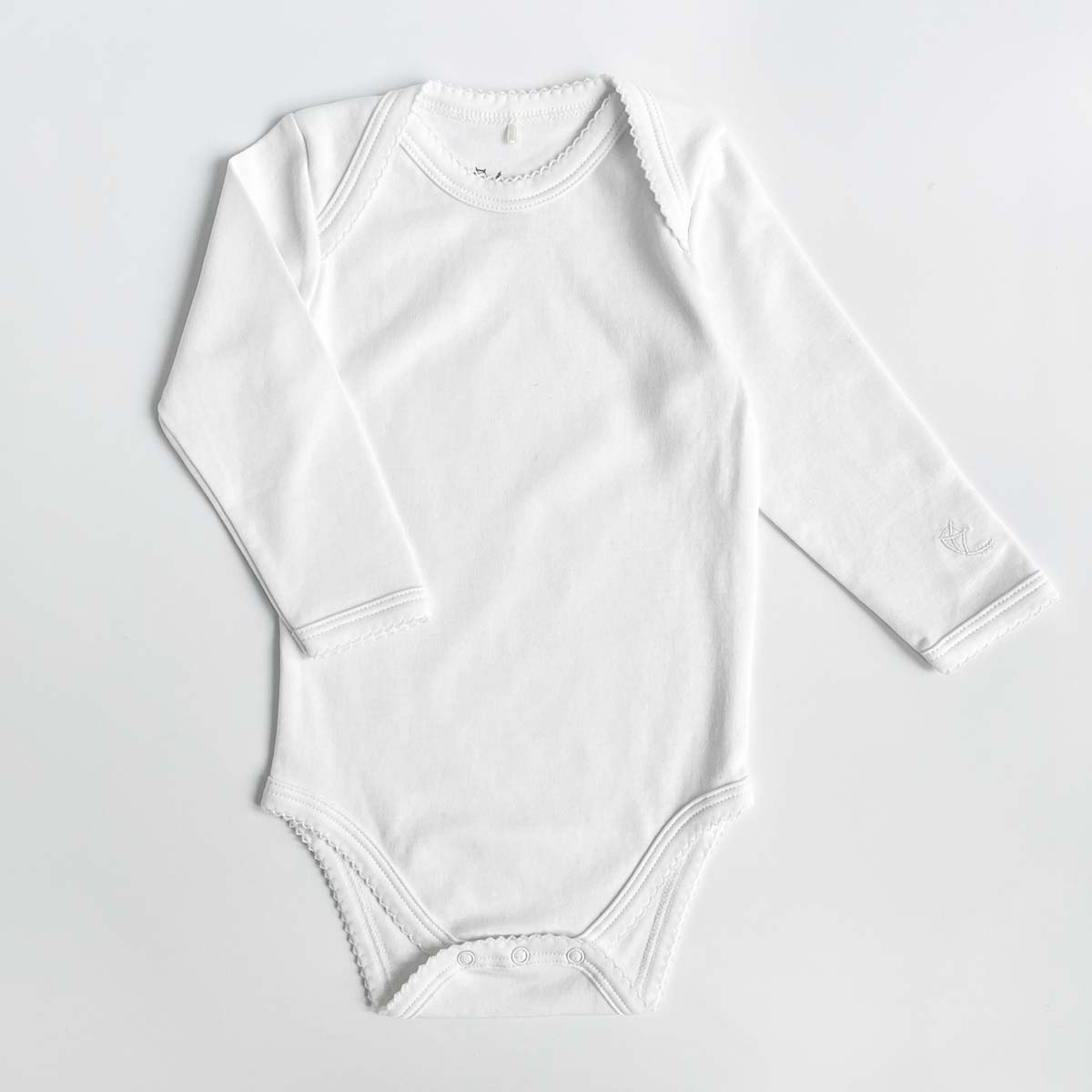 Vit body för baby med spetskant och kuverthals i ekologisk pimabomull
