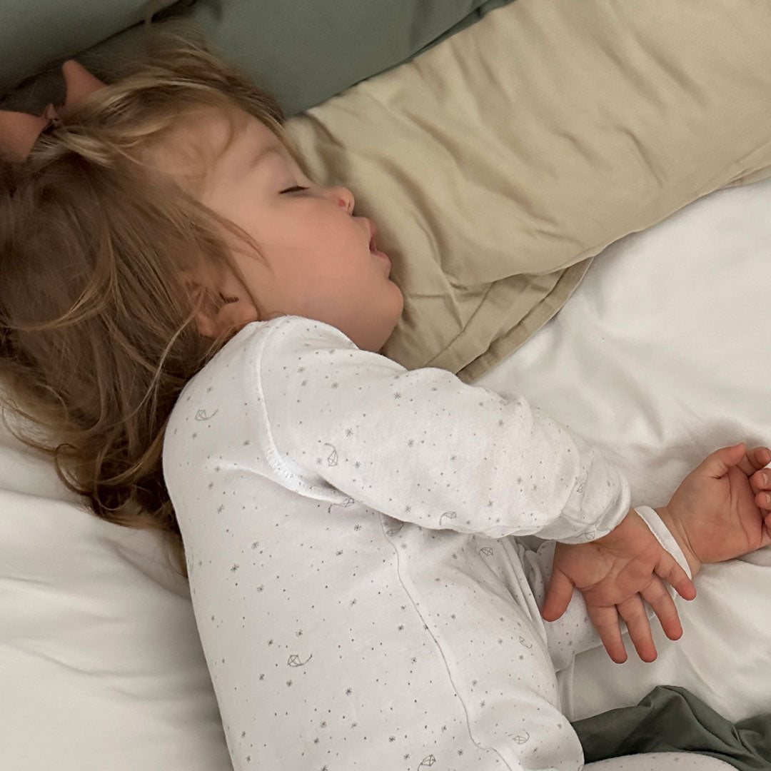 Baby iklädd jumpsuit i vitt med ljusgrått print