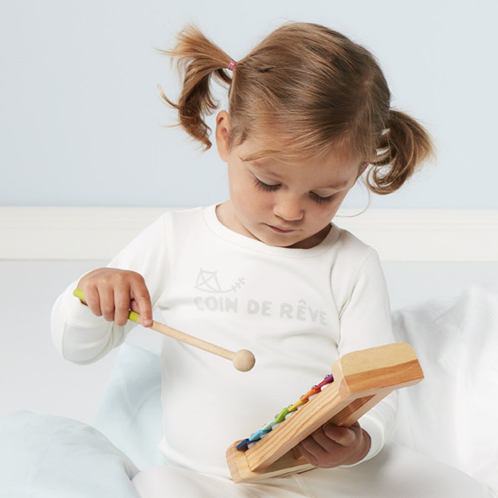 Söt flicka i vit tvådelad bomullspyjamas med Coin de Rêve tryckt på bröstet