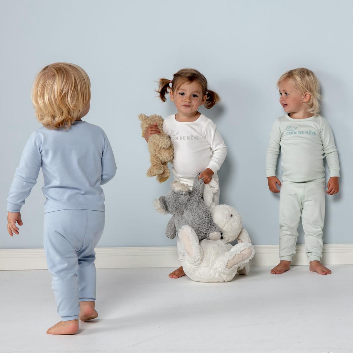 Tre söta barn som har på sig pyjamasar i ter olika färger