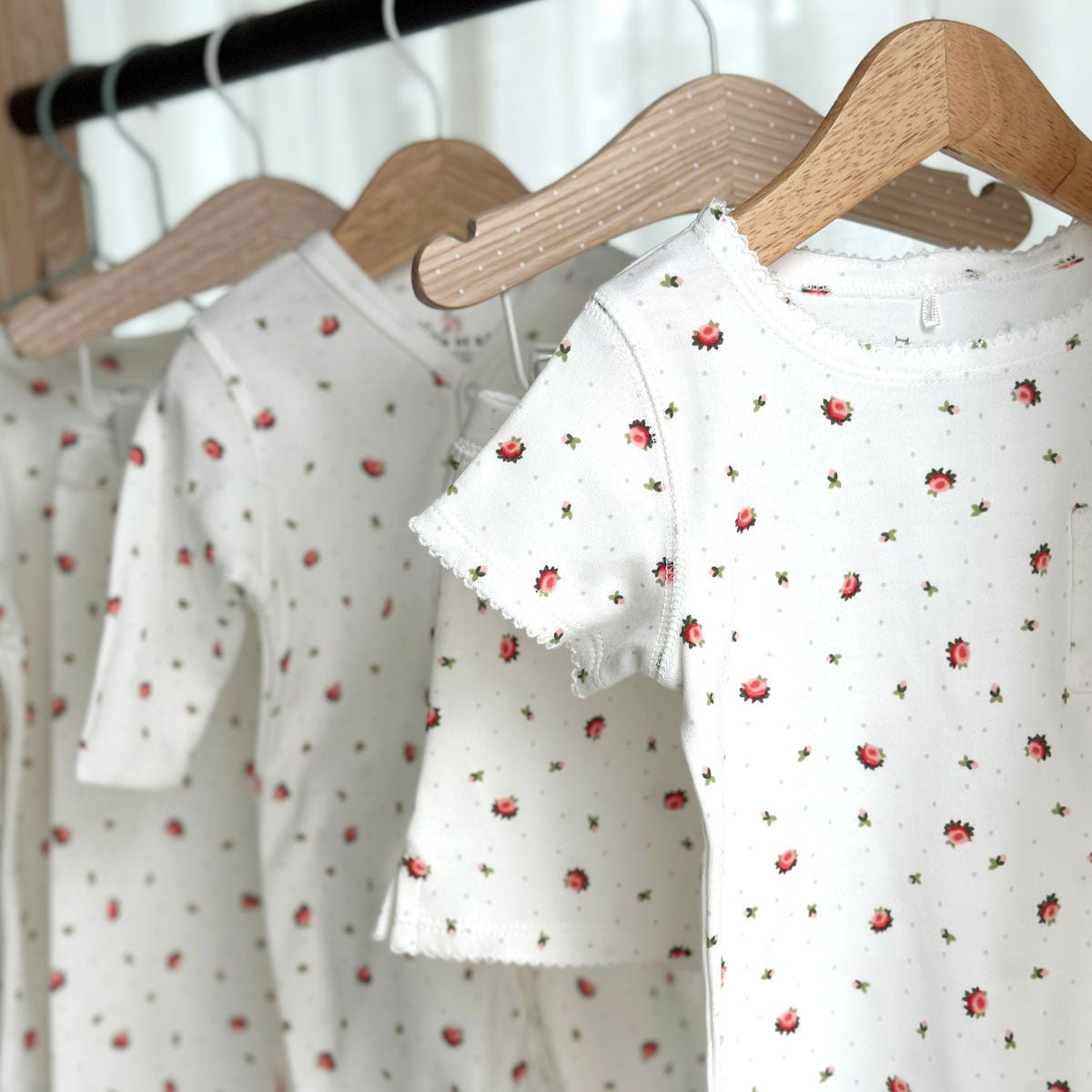 Olika klädesplagg med vårt blommiga print Rose Meadow upphöngda på galge