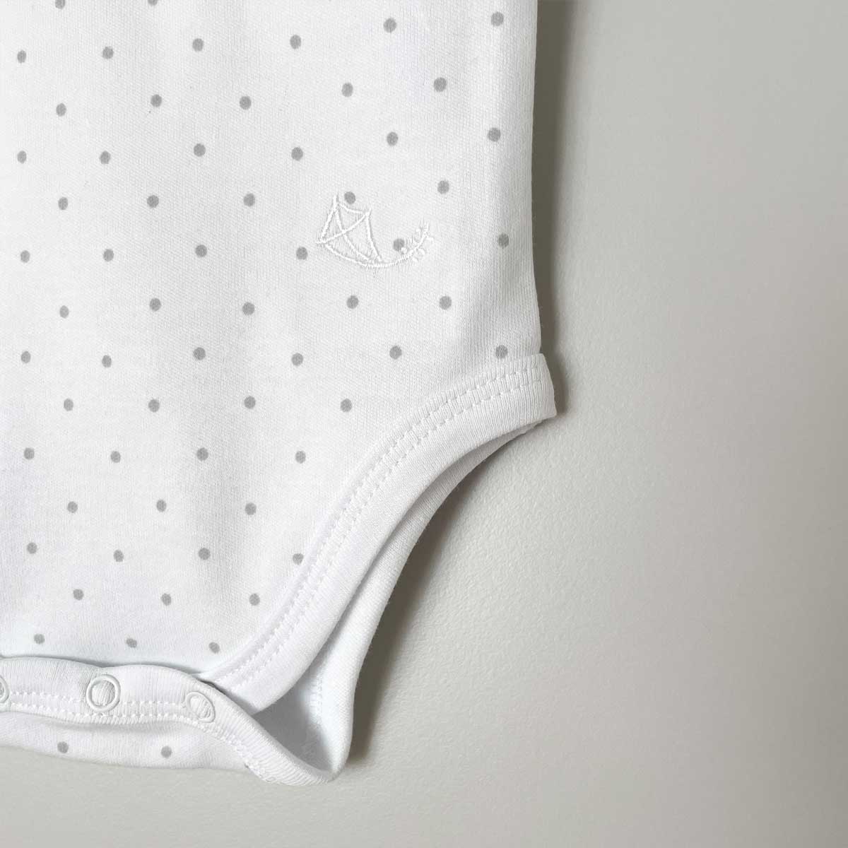 Brodyrdetalj från ärmlös body i ekologisk bomull, vit med grå prickar