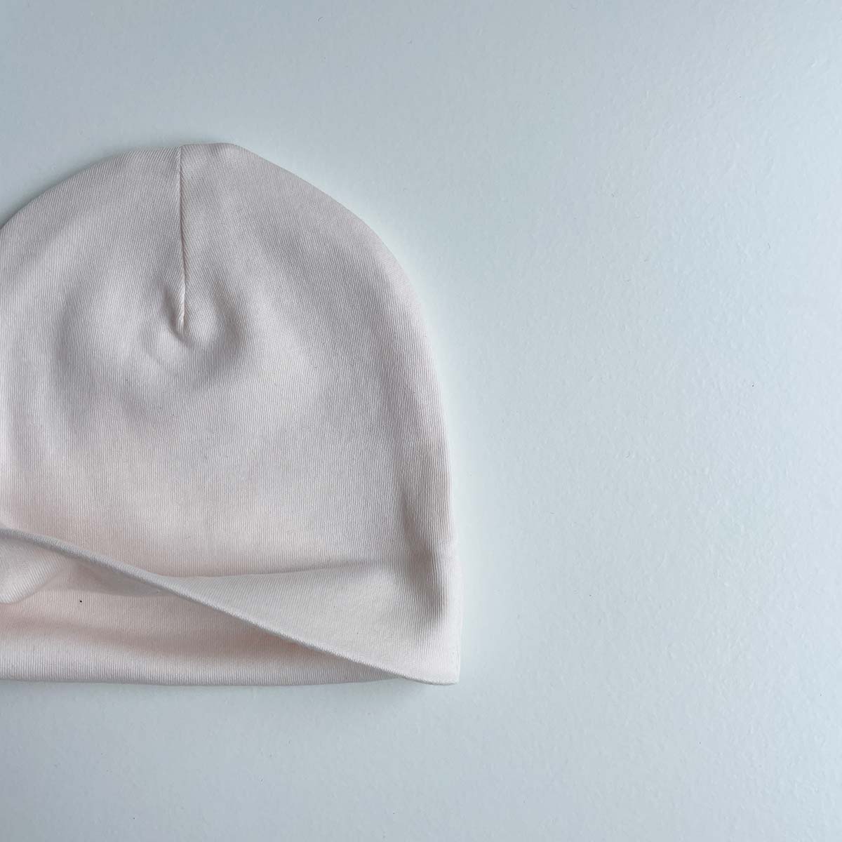 Nedvikt krämrosa babymössa i mjuk ekologisk pimabomull