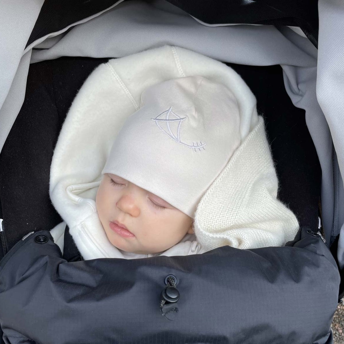 Mössa i ekologisk pimabomull med broderad drake i färg pebble