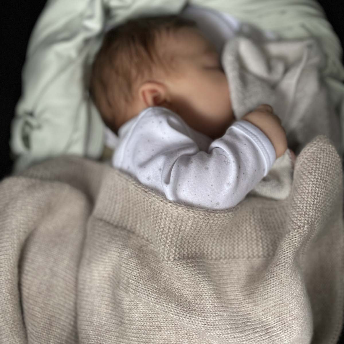 Sovande baby med stickad filt i baby alpaca i färgen oatmeal