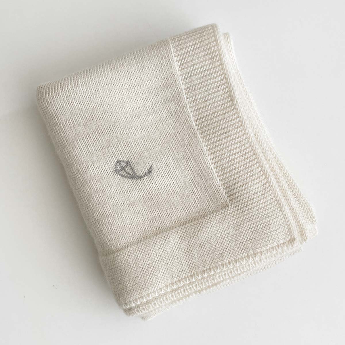 Krämvit stickad babyfilt i premium alpaca-ull med broderad logo