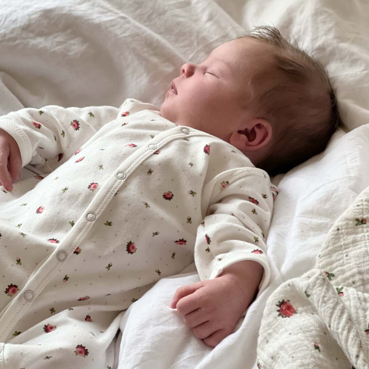 Sovande bebis i jumpsuit i ekologisk och GOTS-certifierad bomull med blommigt print