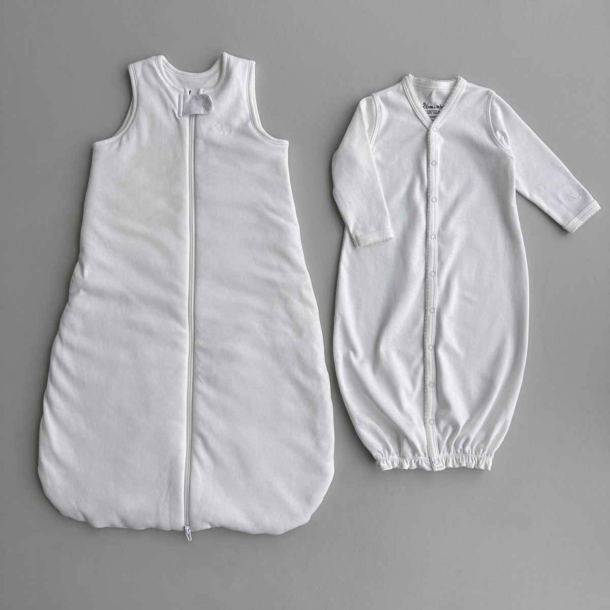 Krämvit Sovpåse (sleep sack) bredvid krämvit sovpåse (sleeping gown) på plan grå yta.