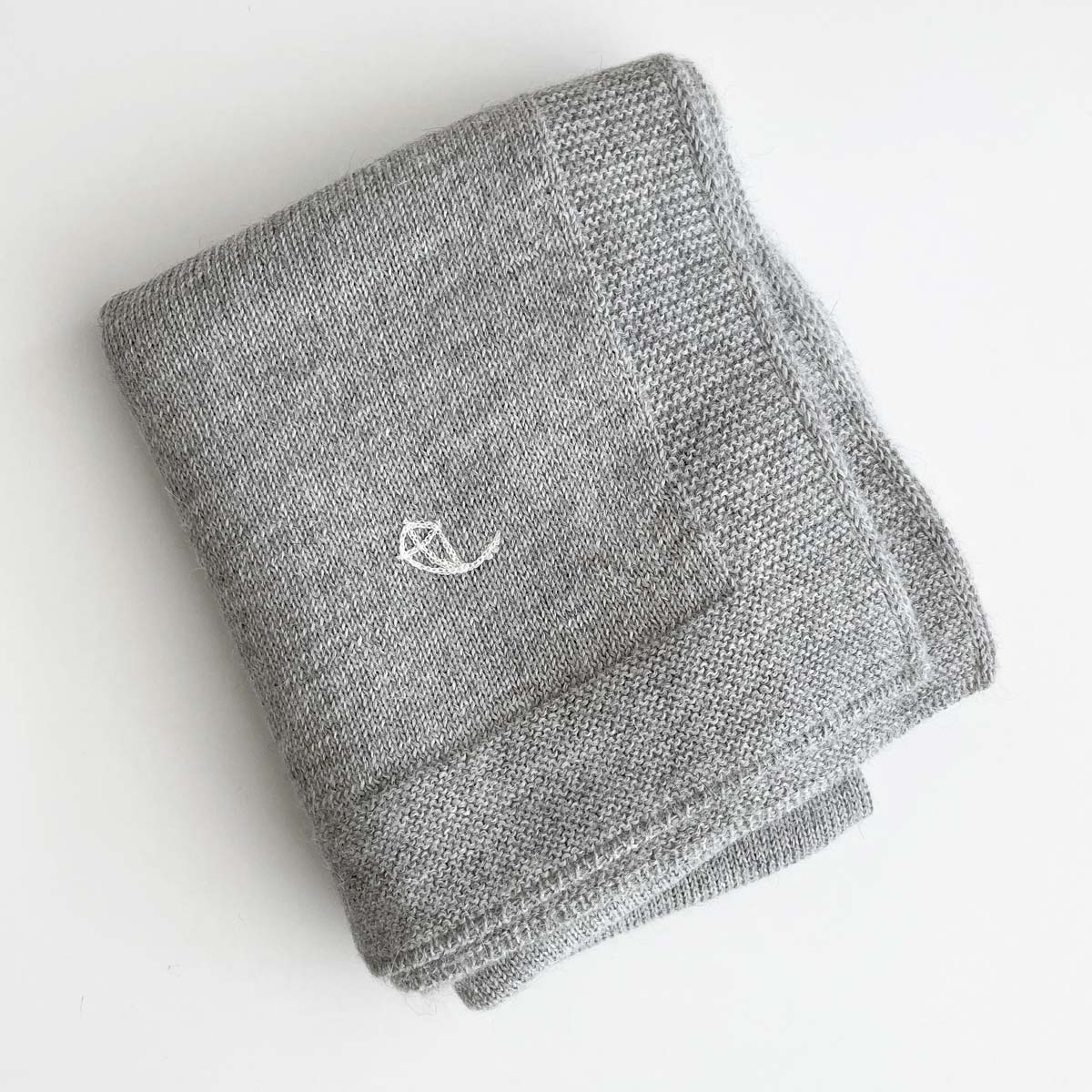 Grå stickad babyfilt i premium alpaca-ull med broderad logo